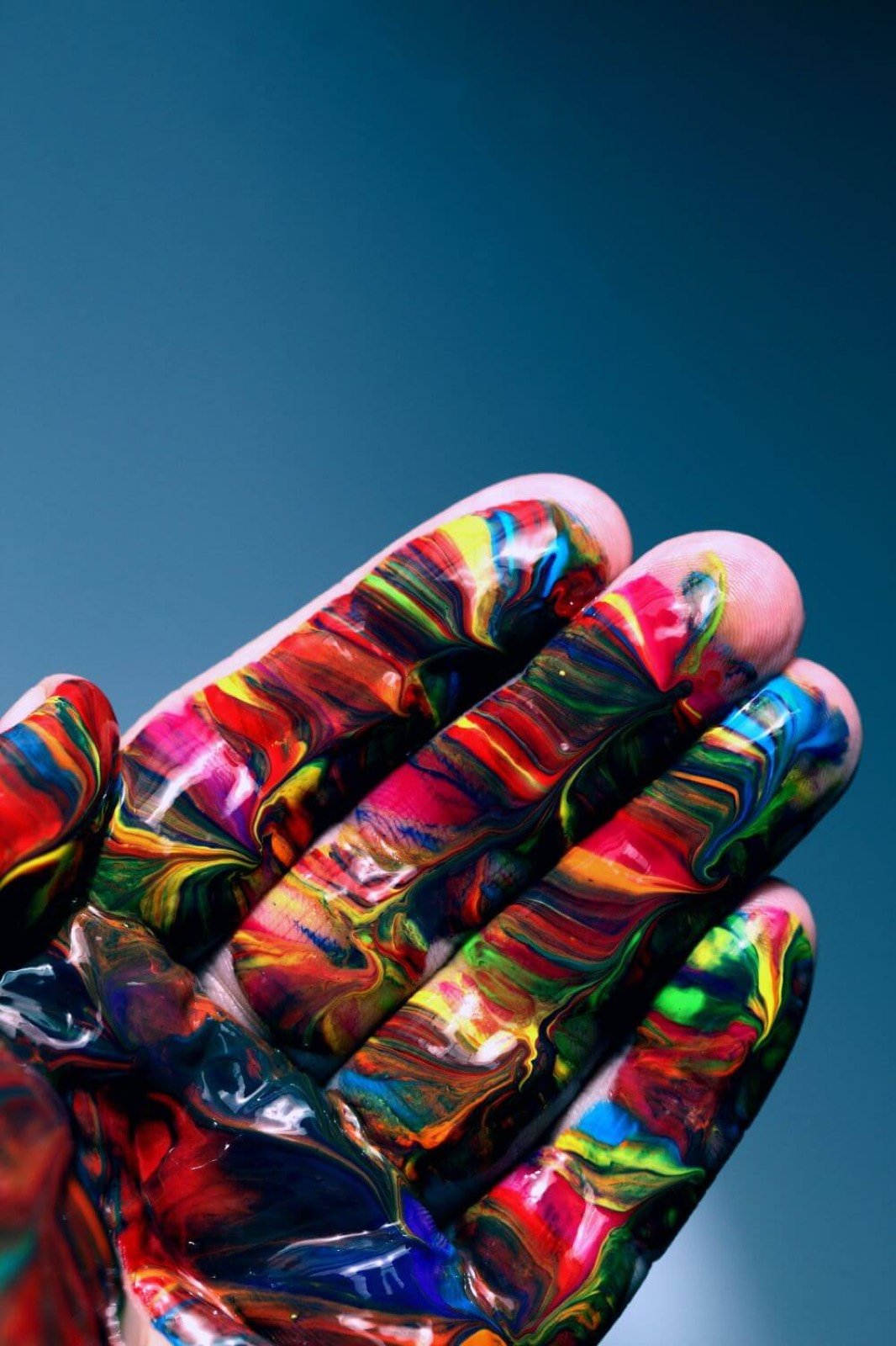Hand covered in swirls of colourful paint